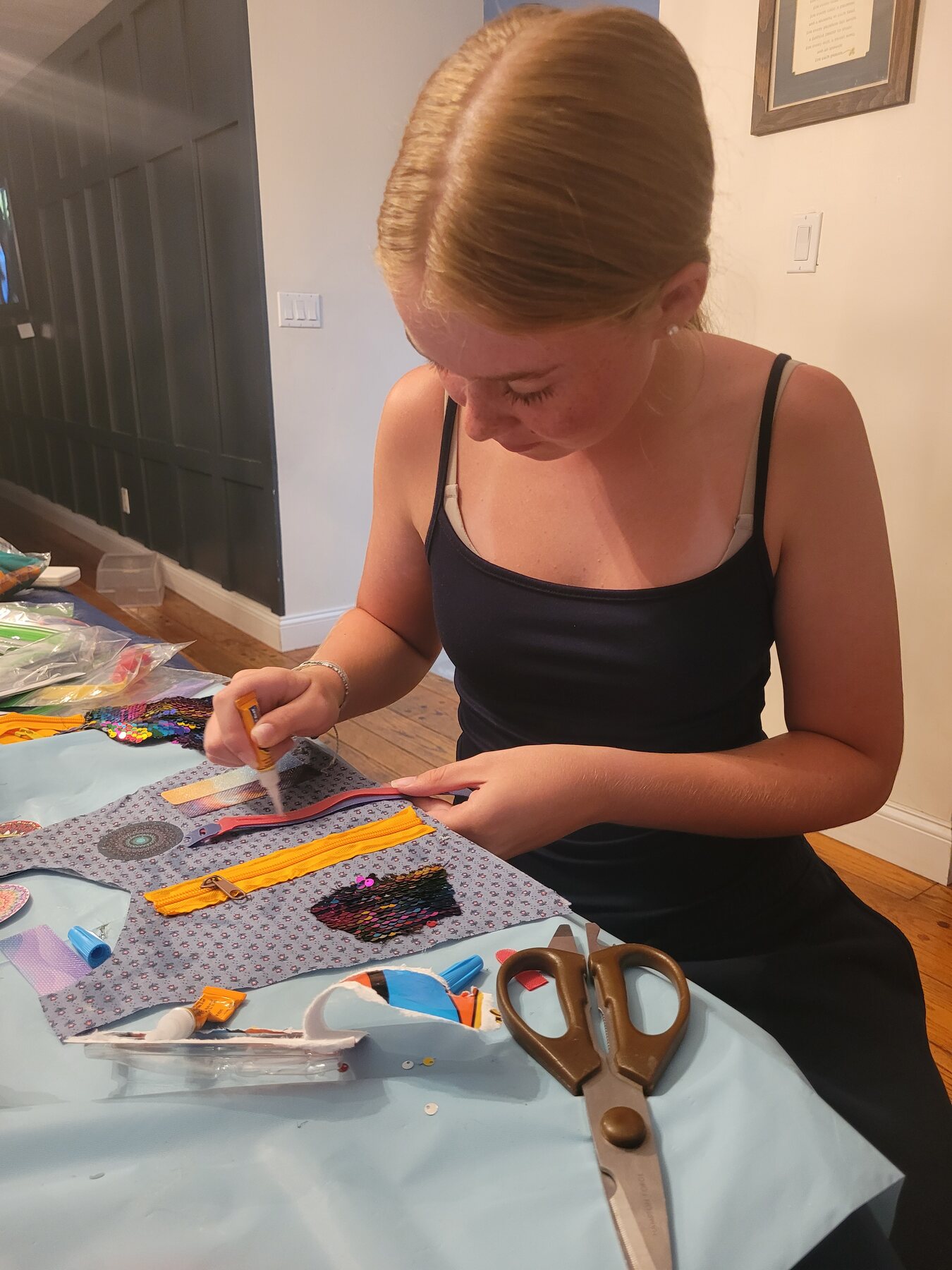Hands attaching colorful sensory pieces to a cape with adhesives