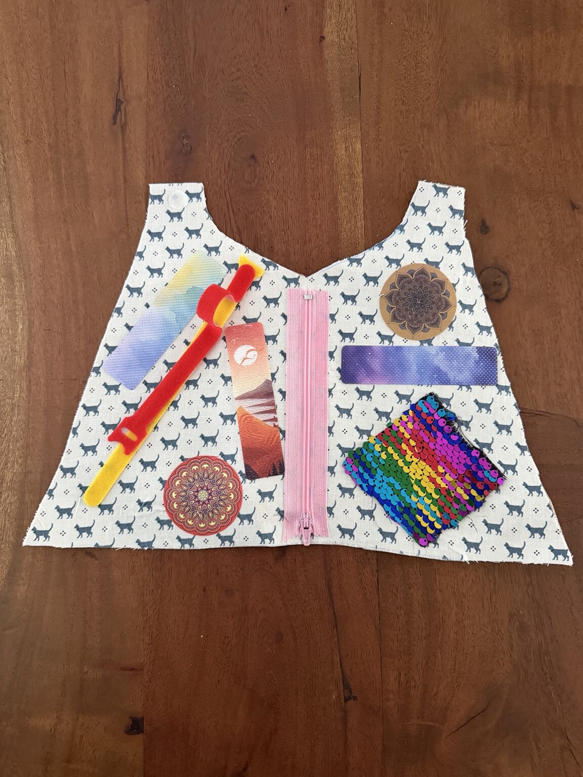 A completed sensory cape with a zipper, Velcro, textured strips, sequins, and decorative pieces